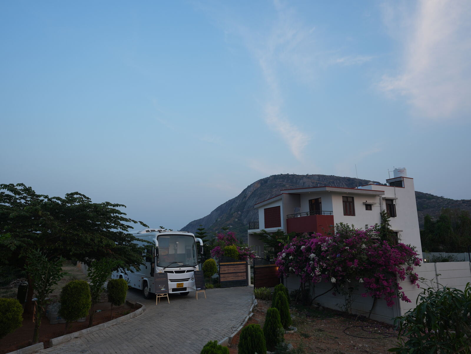Ratha caravan on rent in Bangalore — White Caravan parked at hillside property